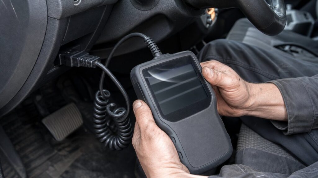 Диагностический сканер подключён к разъёму OBD-II в салоне автомобиля