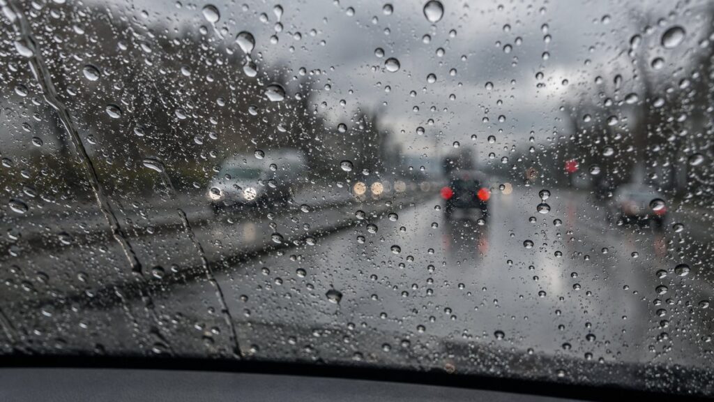 Капли воды скатываются по лобовому стеклу автомобиля с гидрофобным покрытием